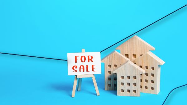 Pequeñas casas de madera con un pequeño cartel que se encuentra anunciando que se trata de una maqueta de casas en venta.