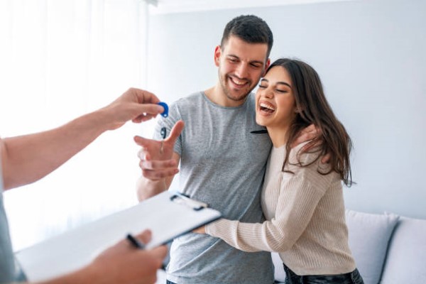 Pareja feliz de jóvenes que acaban de recibir su propiedad después del proceso que siguieron para obtener casas en venta.